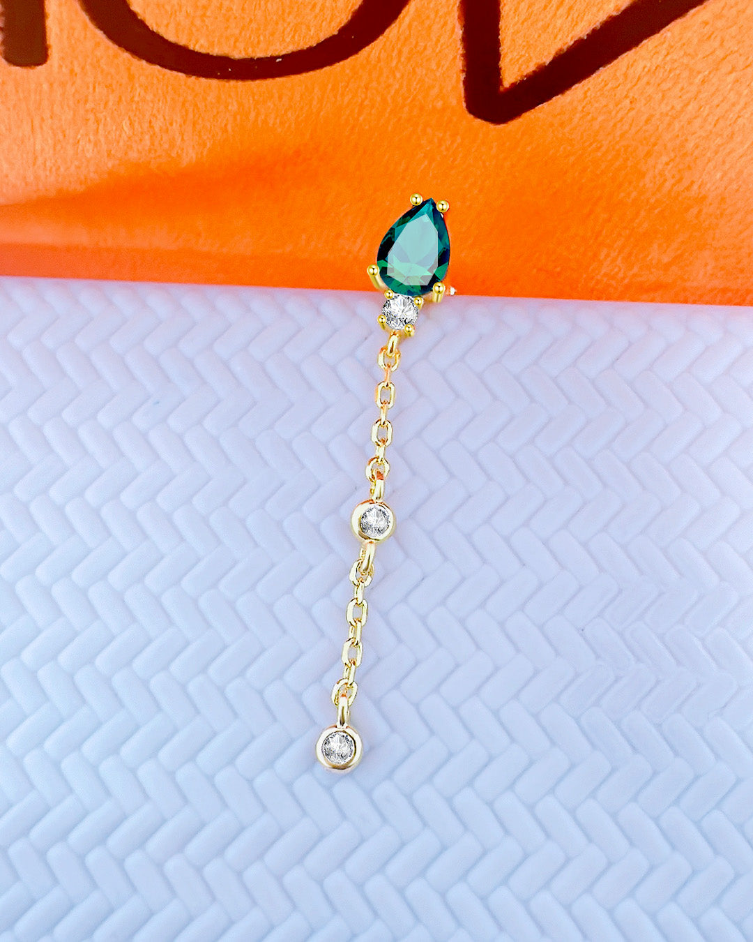 CZ emerald color pear shape stud earring with dngling chain and two white CZ in bezel setting.