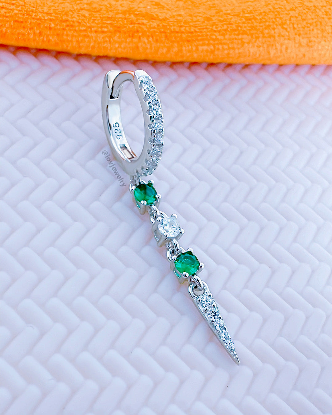 CZ huggie hoop with dangling emerald color and white stones.