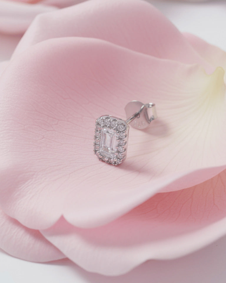 emerald cut stone in a halo setting stud earring.