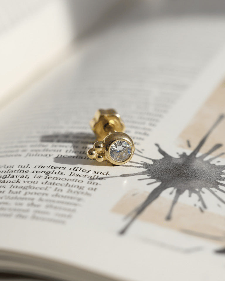 round CZ in bezel setting with three beads piercing.