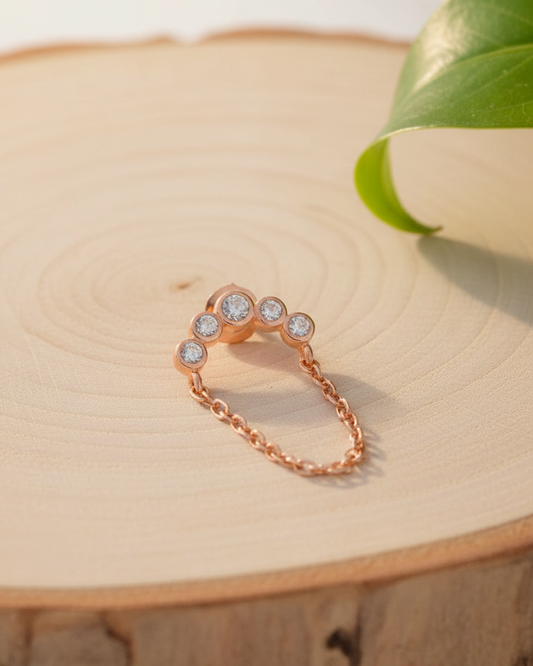 Rosegold curved bar of round CZ in bezel setting with dangling chain.