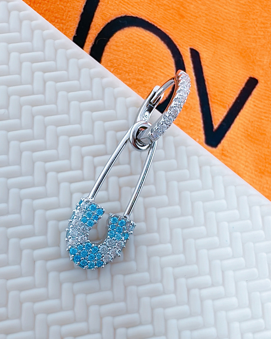 huggie hoop with dangling pin shape.