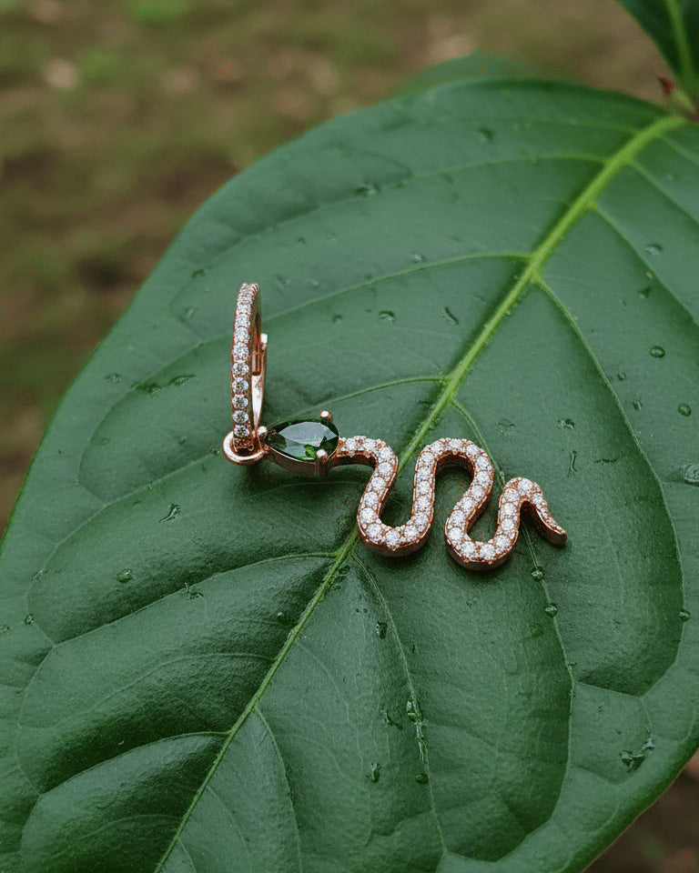 huggie hoop with dangling snake shape plated with rose gold.