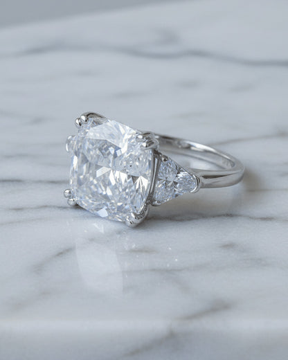 Cushion shape solitaire ring with two trillion cut side stones.