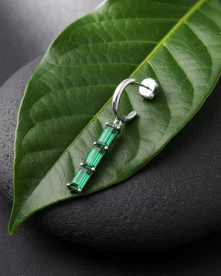plain huggie hoop with dangling emerald and ruby color bar.