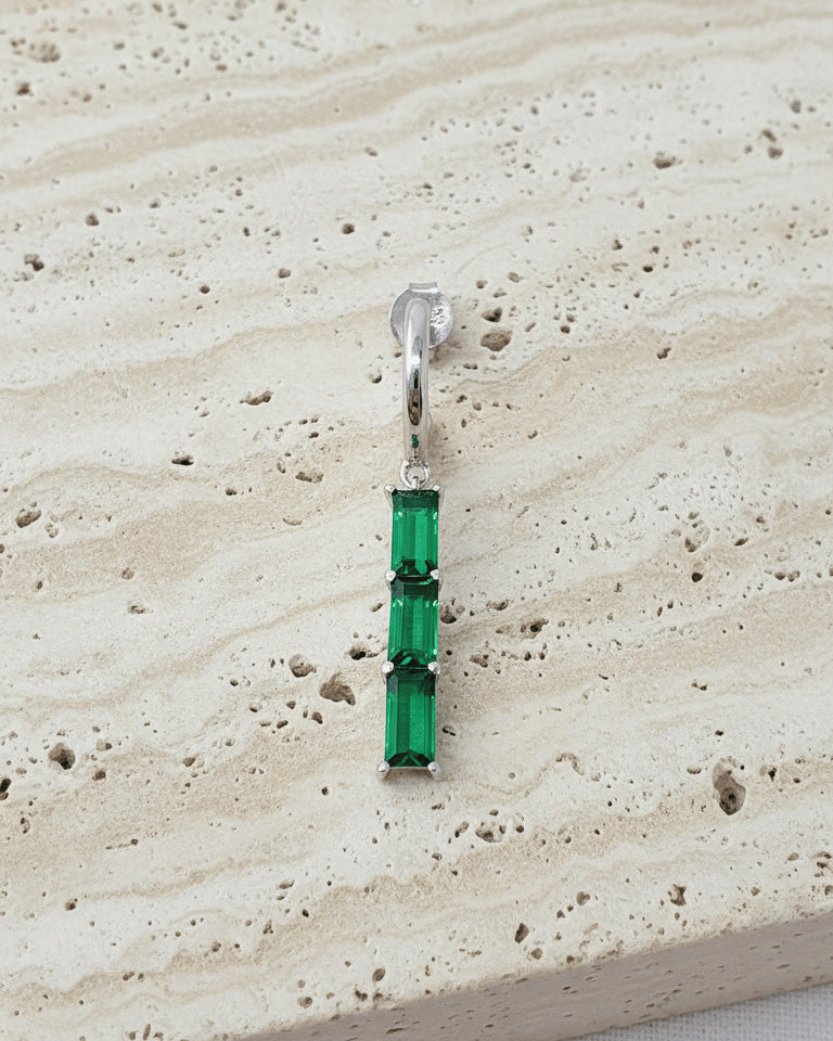 plain huggie hoop with dangling emerald and ruby color bar.