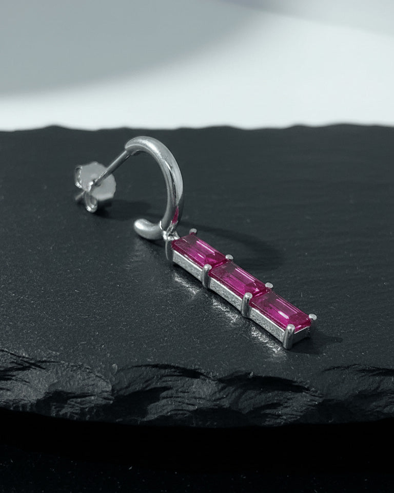 plain huggie hoop with dangling emerald and ruby color bar.