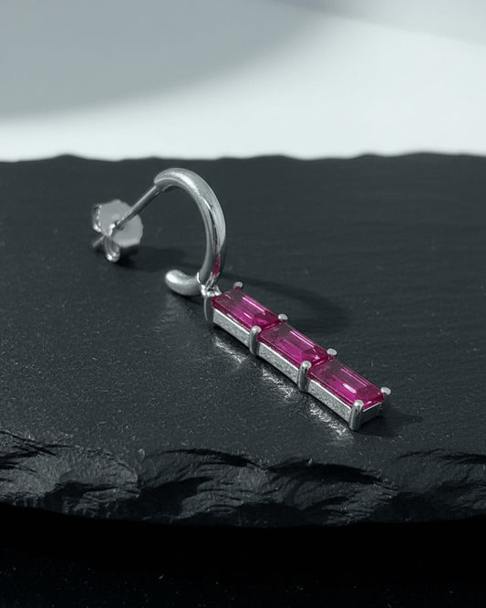 plain huggie hoop with dangling emerald and ruby color bar.