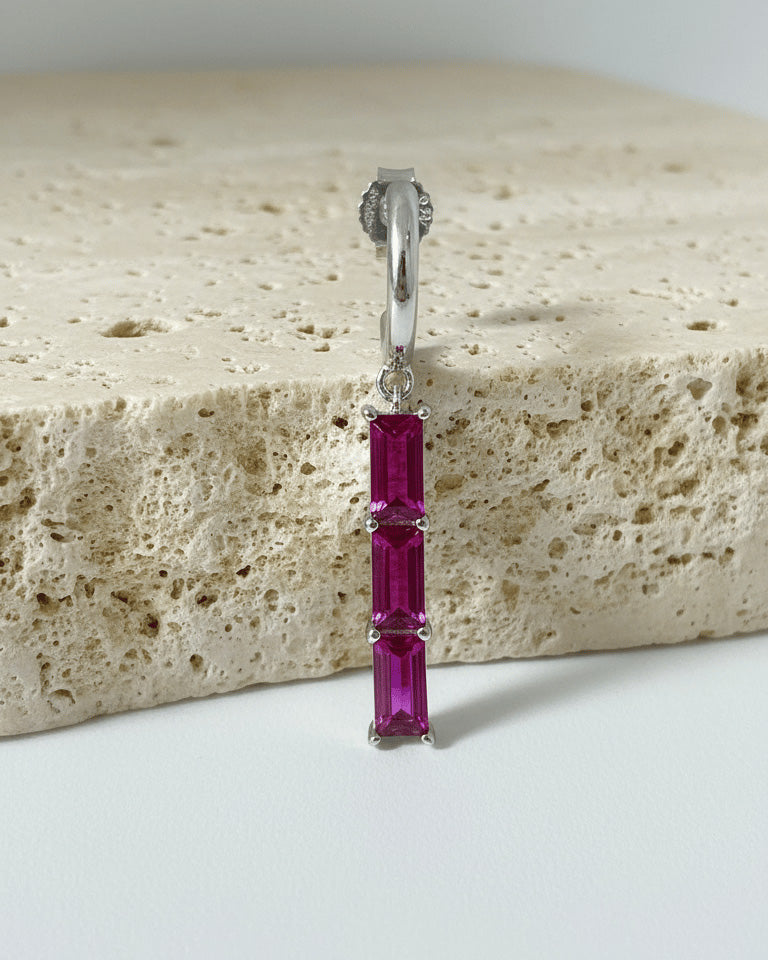 plain huggie hoop with dangling emerald and ruby color bar.