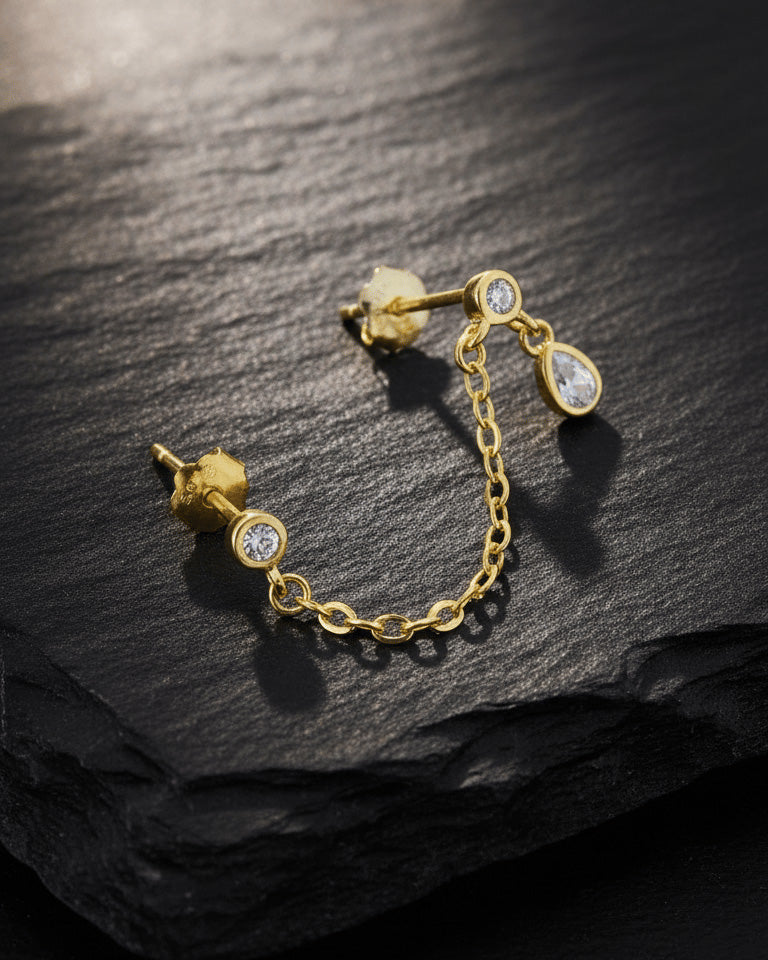 Gold 925 sterling silver double piercing chain earring with round CZ studs and pear-shaped CZ drop on slate background