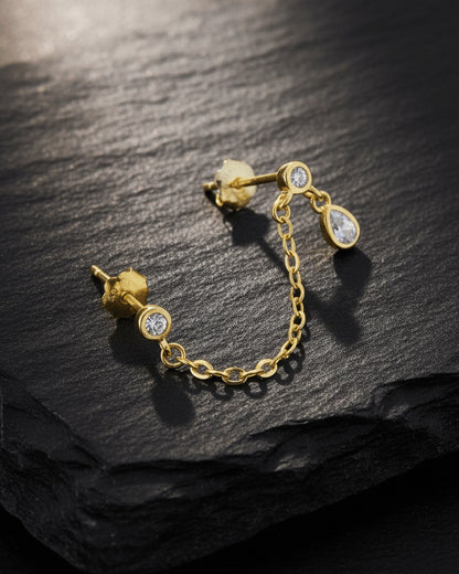 Gold 925 sterling silver double piercing chain earring with round CZ studs and pear-shaped CZ drop on slate background