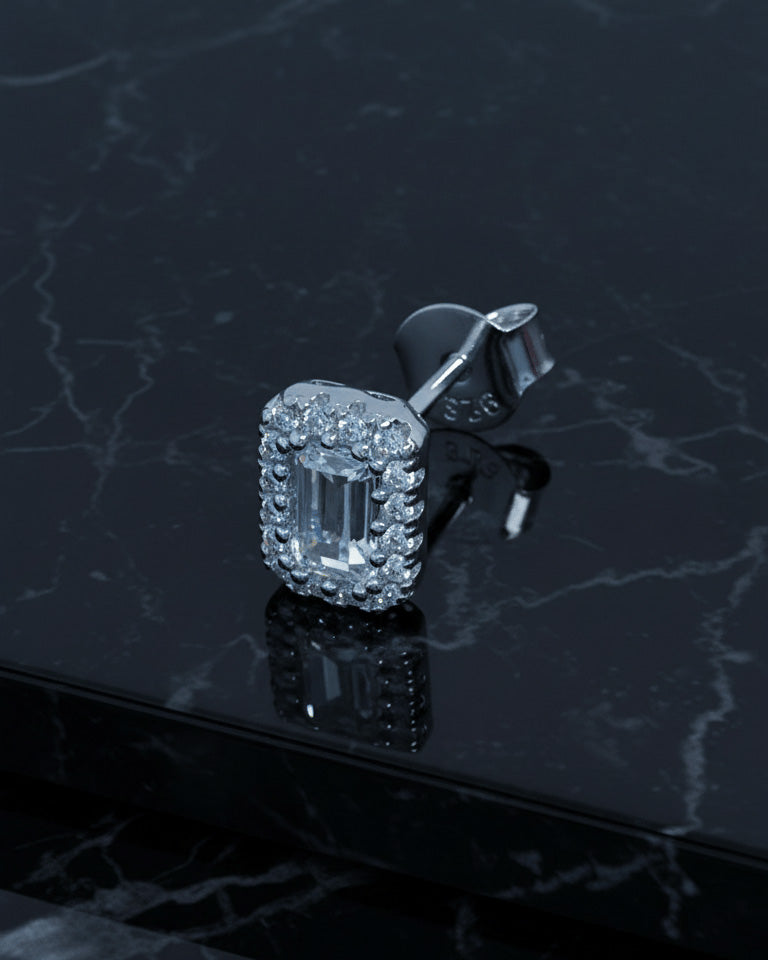 emerald cut stone in a halo setting stud earring.