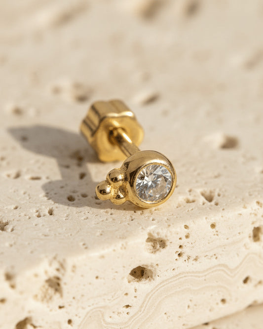 round CZ in bezel setting with three beads piercing.