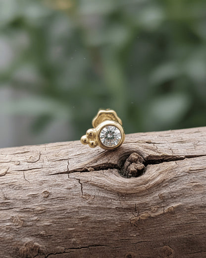 round CZ in bezel setting with three beads piercing.