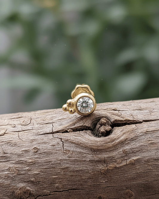 round CZ in bezel setting with three beads piercing.