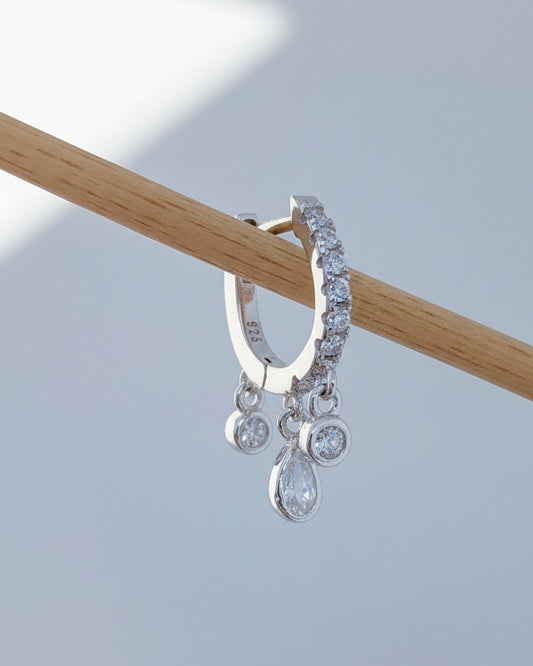 CZ huggie hoop with three dangling stones in bezel setting.
