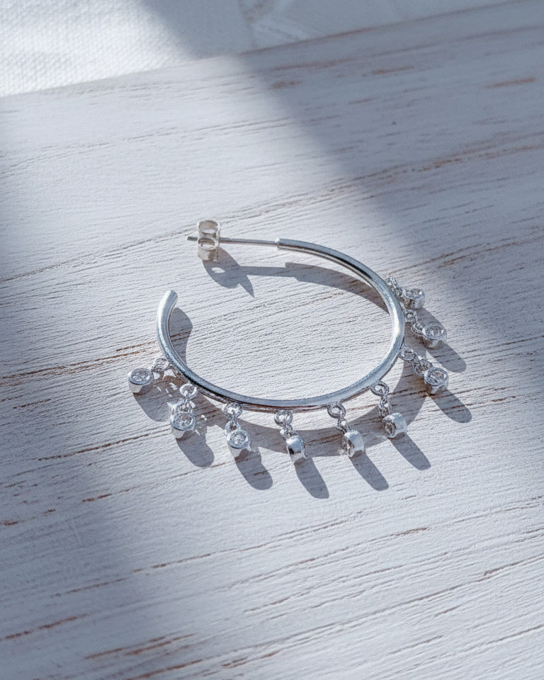 Plain hoops with dangling CZ in bezel setting.