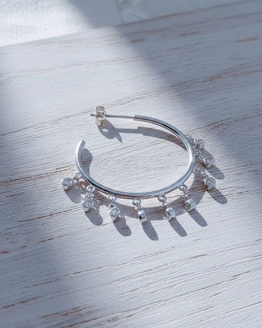Plain hoops with dangling CZ in bezel setting.