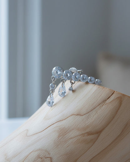 Round graduated CZ bar with dangling pierced pear shapes.