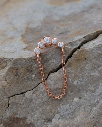Rosegold curved bar of round CZ in bezel setting with dangling chain.