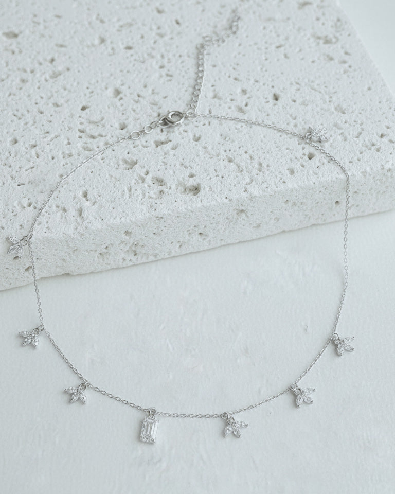 delicate necklace of dangling lotus shape and emerald cut stone.