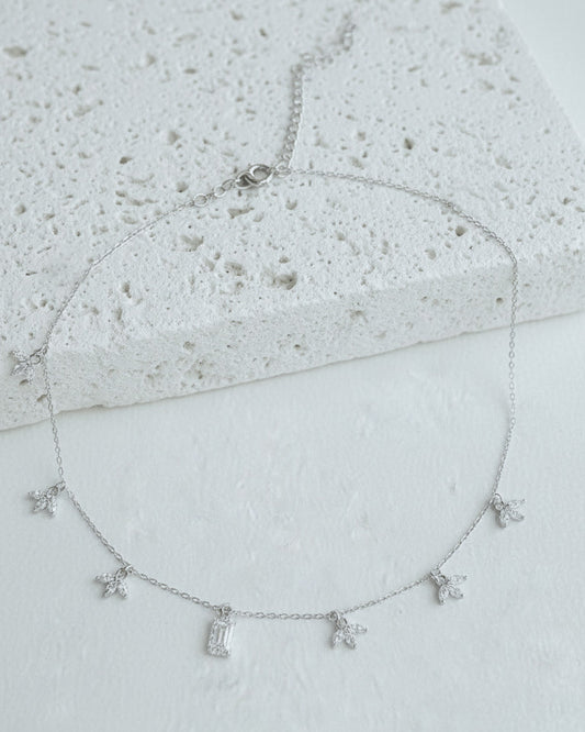 delicate necklace of dangling lotus shape and emerald cut stone.