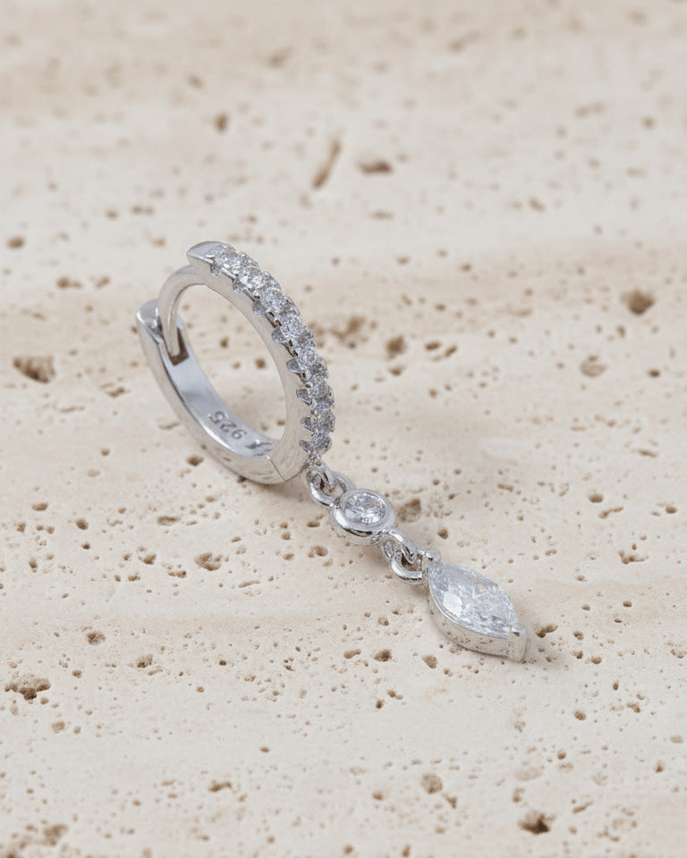 CZ huggie hoop with dangling white and emerald color stones.