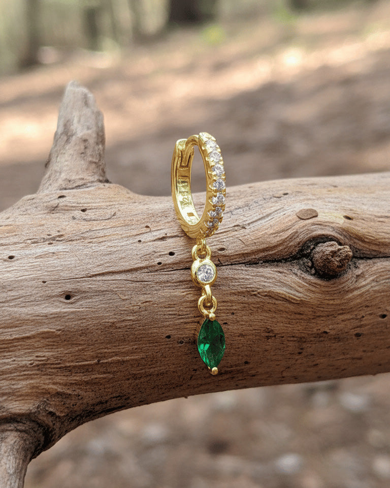 CZ huggie hoop with dangling white and emerald color stones.