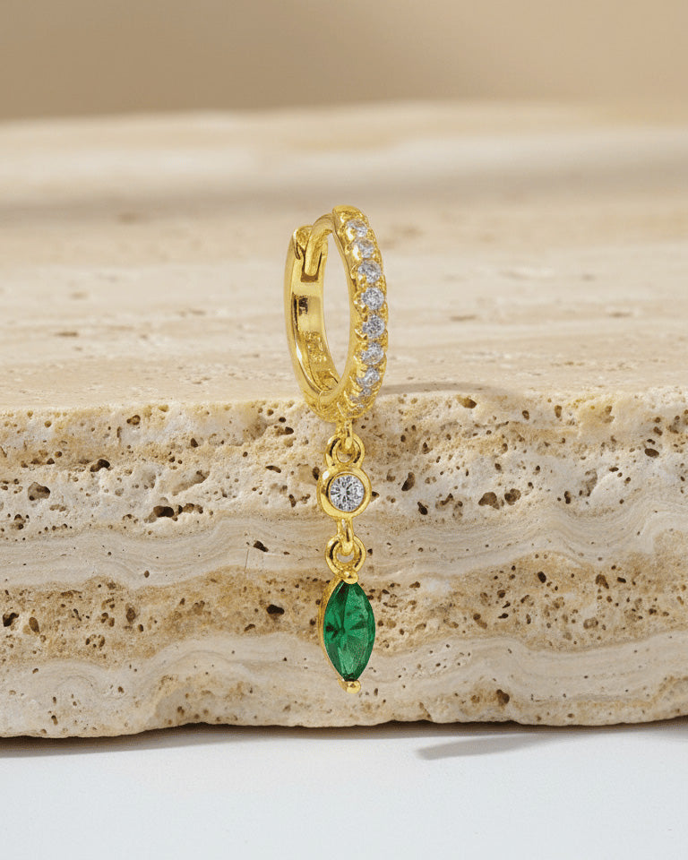 CZ huggie hoop with dangling white and emerald color stones.
