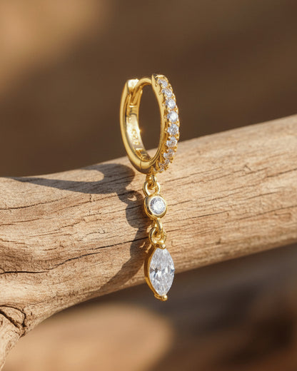CZ huggie hoop with dangling white and emerald color stones.