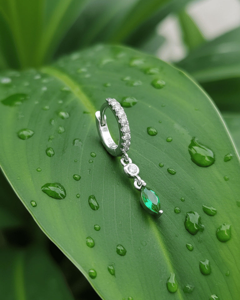 CZ huggie hoop with dangling white and emerald color stones.