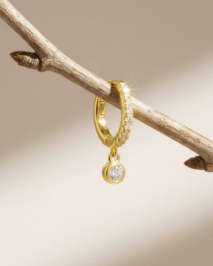8 mm CZ huggie hoop earring with dangling round stone in bezel setting.