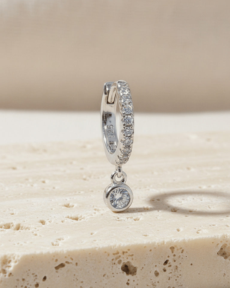 8 mm CZ huggie hoop earring with dangling round stone in bezel setting.