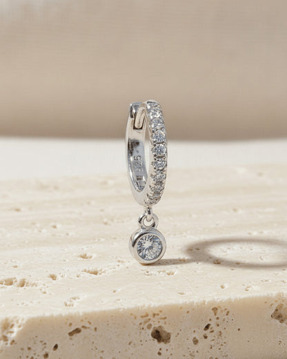 8 mm CZ huggie hoop earring with dangling round stone in bezel setting.