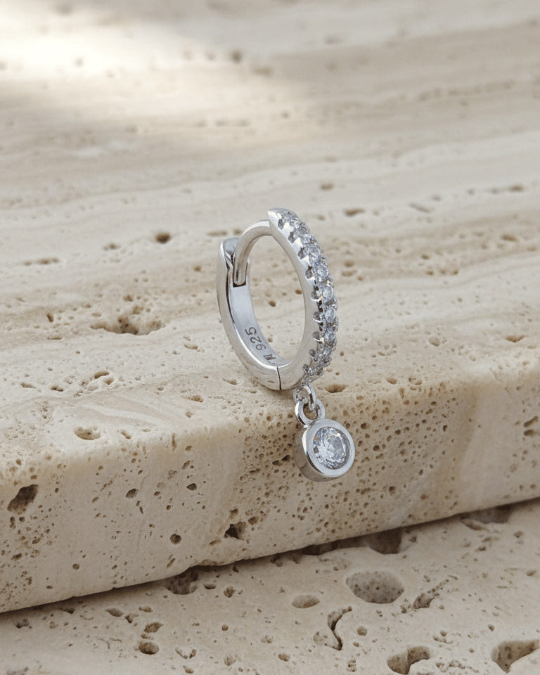 8 mm CZ huggie hoop earring with dangling round stone in bezel setting.