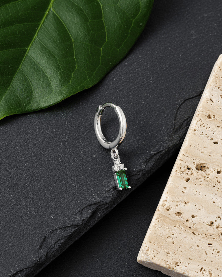 plain silver hoop with dangling emerald cut green stone.
