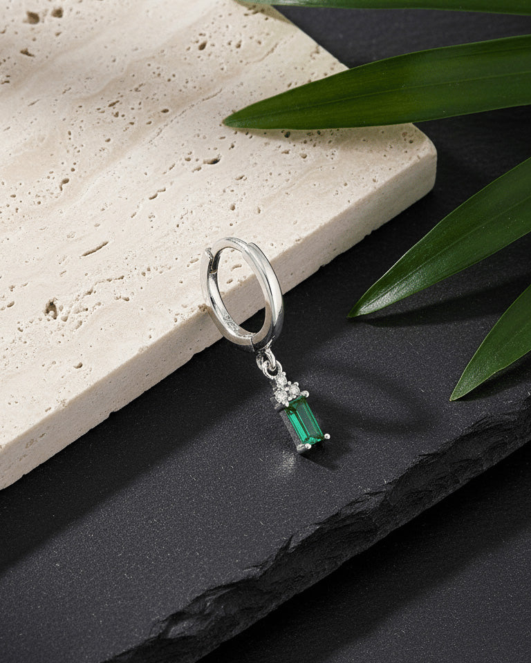 plain silver hoop with dangling emerald cut green stone.