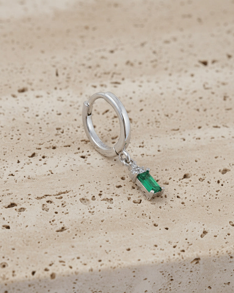 plain silver hoop with dangling emerald cut green stone.