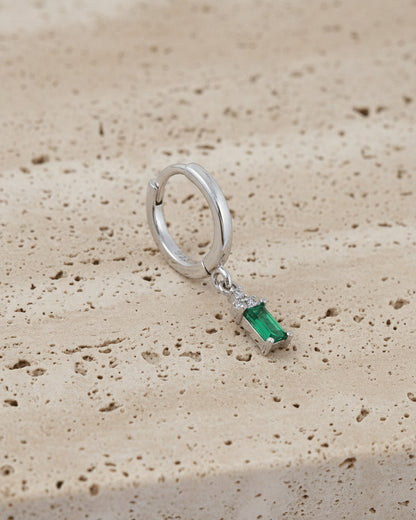 plain silver hoop with dangling emerald cut green stone.