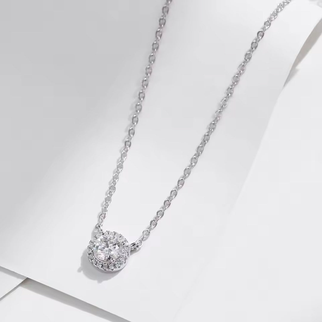 Silver necklace with a round diamond pendant on a light gray background