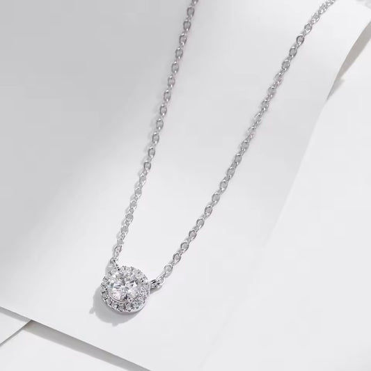 Silver necklace with a round diamond pendant on a light gray background