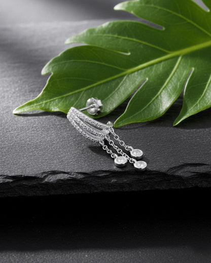 triple half huggie hoop with dangling chains of bezel setting round stones.