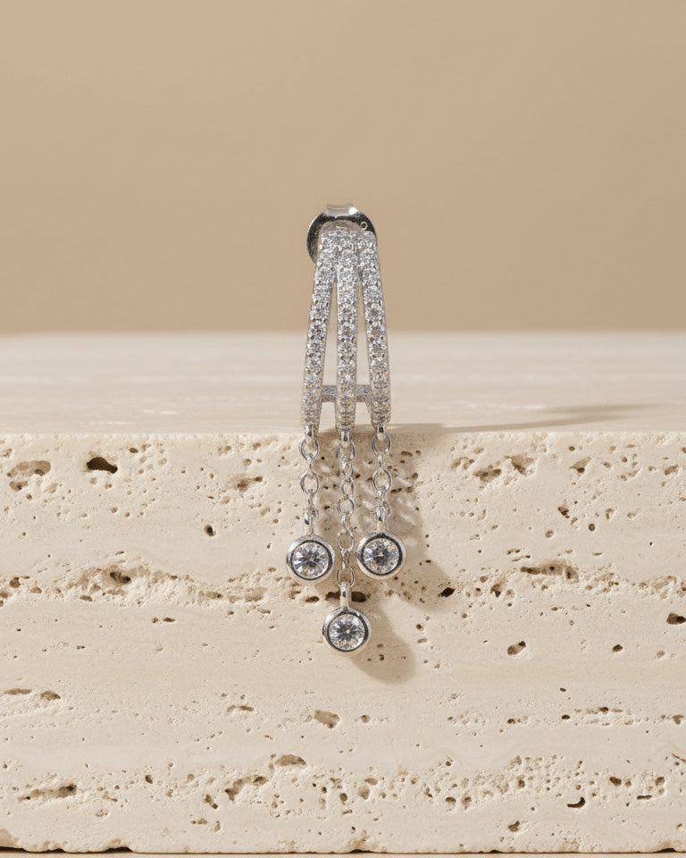 triple half huggie hoop with dangling chains of bezel setting round stones.