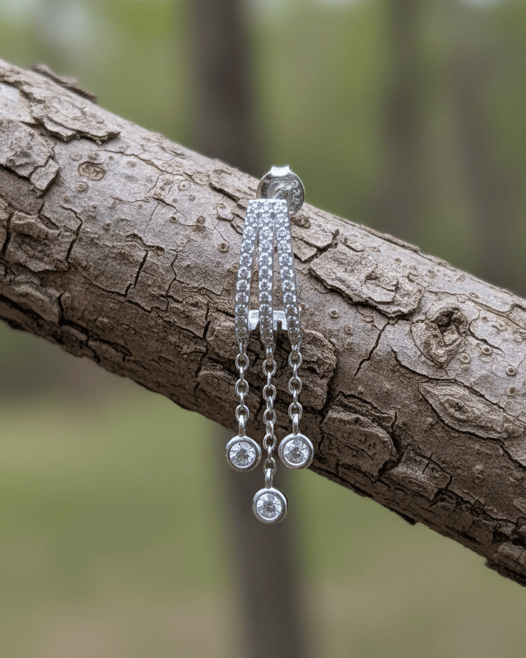 triple half huggie hoop with dangling chains of bezel setting round stones.